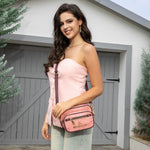 WOMEN IN A PINK SLEEVELESS TOP AND BLUE JEANS SHORTS WEARING OUR MARGOT 2 PIECE CROSSBODY IN PINK SET IN A MODERN BACKGROUND.