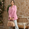 Woman in pink blazer and floral top with hair in a bun and star earrings stylishly holding a blush pink Nicole Lee Calista dome shaped handbag by the top handle. 