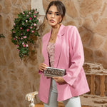 Woman in pink blazer and floral top stylishly posing and showing off her metallic silver Nicole Lee Calista Flap Wallet. 
