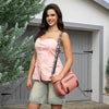 WOMEN IN A PINK SLEEVELESS TOP AND BLUE JEANS SHORTS CARRING OUR MARGOT SHOULDER BAG IN PINK SET IN A MODERN BACKGROUND.