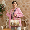 Woman in pink blazer and light blue denim jeans smiling away while holding a Nicole Lee Calista handbag in metallic gold with gold-tone hardware details. The woman is carrying it by the top handles while also wearing the logo webbed shoulder strap to show varied carrying options and versatility. Set against a modern, rustic background with a bench and flowers hanging behind her. 