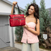 WOMEN IN A PINK SLEEVELESS TOP AND BLUE JEANS SHORT SMILING TO OUR MARGOT TOTE IN RED SET IN A MODERN BACKGROUND.