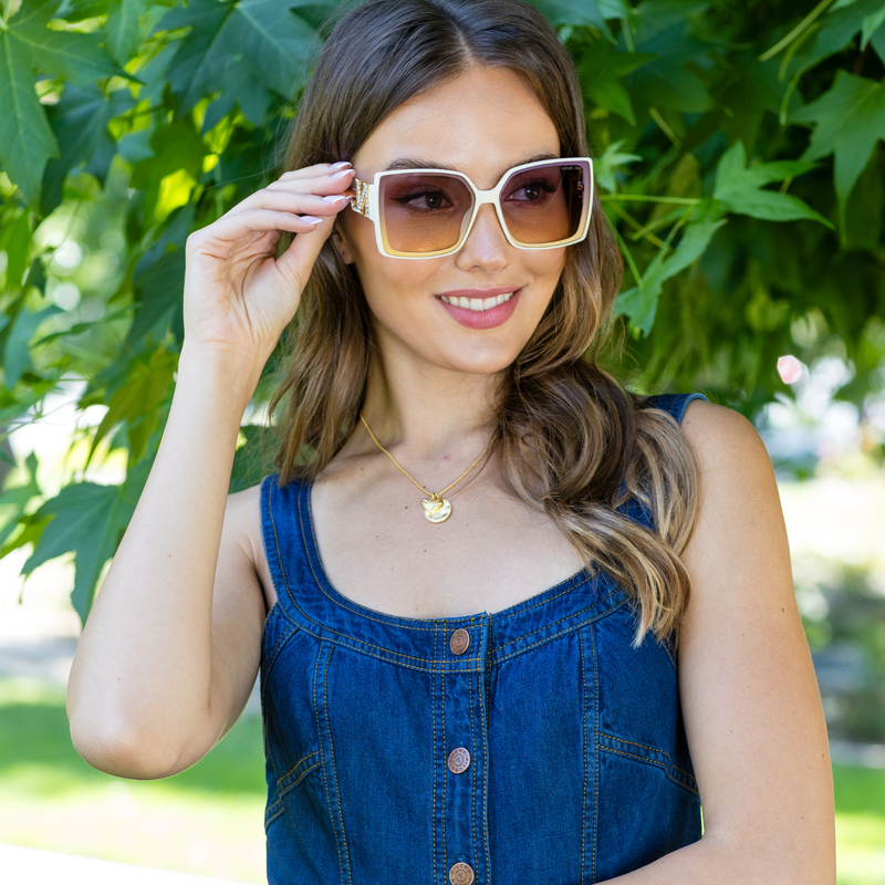 woman in denim smiling while holding our NL square sunglasses.