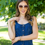 woman in denim dress stylishly posing and showing off our Nicole Lee
 white sunglasses set on a greenery  background.