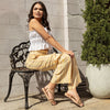 WOMEN SITTING IN A RUSTIC BENCH WEARING OUR DANI RHINESTONE SANDALS IN GOLD.