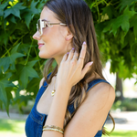 woman in denim dress stylishly posing and gently touching her hair with our white square sunglasses set on a greenery background.