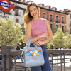 Woman in a mauve sleeveless top holding in her arm Our blue Floral Pop Tote Bag with floral design in an urban setting
