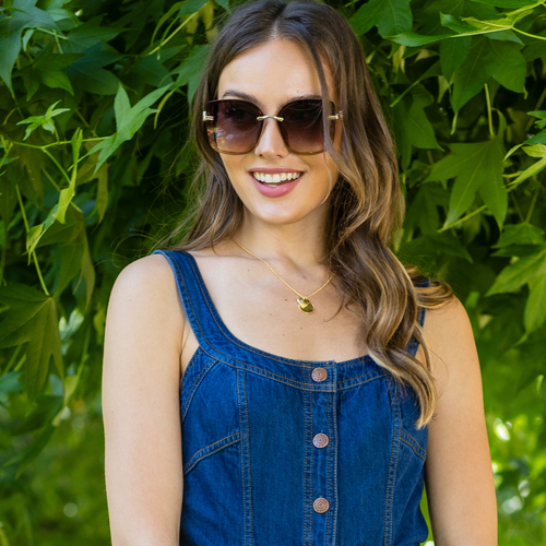 woman in denim dress stylishly posing and showing off our Nicole Lee
Glitter sunglasses set on a greenery  background.