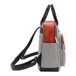 Side profile of the Nicole Lee vegan leather Violet Blossoms backpack, part of the VIOLET BLOSSOM 3 PIECE SET (Backpack, Crossbody, Wallet). Gray with black and deep orange accents. Side slip pockets and zip closures to keep items protected and secure. 