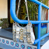 Product shot of the Nicole Lee Calista shoulder bag in metallic silver hanging around a stylish blue metal fence in a trendy outside spot.