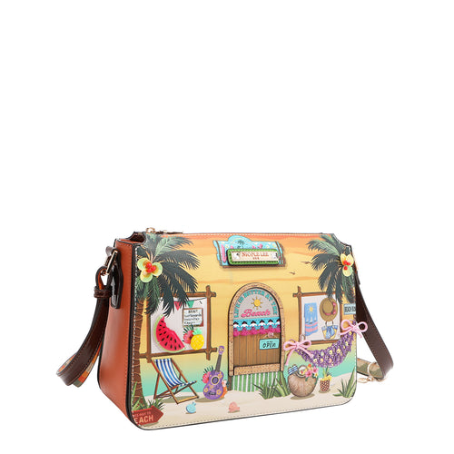 Our Sun and Sand Crossbody bag with a tropical design featuring a beach hut, palm trees, and beach items set on a white background.