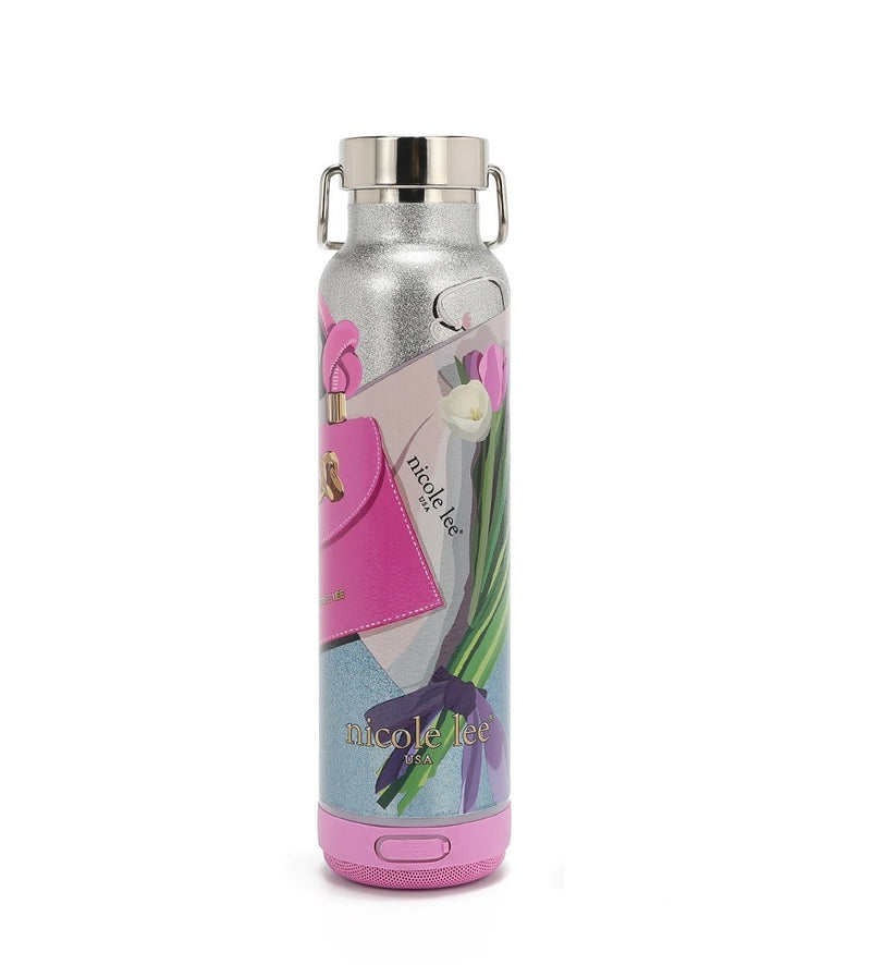 THE TUMBLER HAS A CYLINDRICAL SHAPE WITH A SCREW CAP. IN THE VIOLET BLOSSOM PRINT. IT HAS A SILVER GLITTER BACKGROUND. HAS THE IMAGE OF A PINK HANDBAG AND A BOUQUET OF WHITE, PINK, AND PURPLE TULIPS ALL AROUND. AT THE BOTTOM IS A PINK BLUETOOTH SPEAKER.